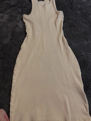 Beige ribbad klänning FB Sister - Säljer en beige ribbad klänning från FB Sister i storlek S. Klänningen är ärmlös med rund halsringning och har en kroppsnära passform. Perfekt för sommardagar och enkel att styla med sneakers eller sandaler.