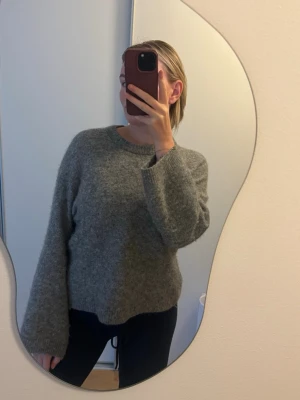 Grå stickad tröja i alpacka ull - Mysig grå stickad tröja med rund halsringning och långa ärmar. Tillverkad i en mjuk blandning av alpacka och ull som ger en fluffig känsla. Perfekt för lager-på-lager och chill dagar. Slutsåld på hemsidan !