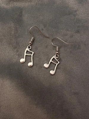 Örhängen Noter Smycke Silver imitation Not -  Söta örhängen i form av noter! Silverimitation. Berlockerna är ca 2,5x 1,1 cm. 