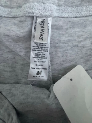 Grå mjukisbyxor från H&M, storlek L - Mysiga grå mjukisbyxor från H&M i storlek L. Tillverkade i en mjuk blandning av bomull, polyester och spandex för extra stretch och komfort. Byxorna har rak passform och resår i midjan, perfekta för chill dagar hemma.