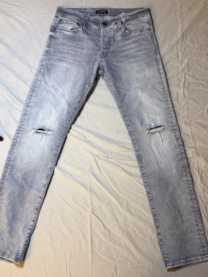 Jack & Jones Glenn jeans ljusgrå – Slim fit – 32/32 – Mycket bra skick (unika slitningar) - Sjukt unika ljusgrå Jack & Jones Glenn slim jeans, storlek 32/32, i mycket bra skick. Riktigt snygga slitningar som ger karaktär och sticker ut på ett stilrent sätt.  Glenn-modellen är känd för sin slim passform och bekväma känsla. Perfekta för streetwear, Y2K-inspirerade outfits eller casual vardagslook.  Mått: Midja: 41 cm Längd: 104 cm  • Märke: Jack & Jones • Modell: Glenn • Passform: Slim  Jack & Jone