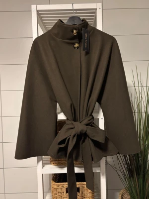 Brun kappa i nytt skick - Kappan är i nytt skick och är helt oanvänd. Kappan är tvättbar i 30 grader och kostar ursprungligen 549kr.