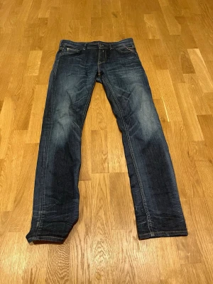 Replay blå jeans straight fit - Säljer ett par klassiska blå jeans från Replay med snygga slitningar och kontrastsömmar. Modellen har raka ben och normal passform. Jeansen har fem fickor och Replay-logga på bakfickan samt patch bak i midjan. Bara att skriva vid intresse!