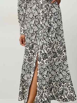 Svartvit blommig långklänning - Säljer en svartvit långklänning med blommigt mönster och knappar framtill. Klänningen har långa ärmar och ett knyt i midjan för snygg passform. Perfekt för dig som gillar detaljer och mönster.