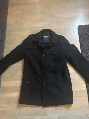 Indigo/indicode, rock - Svart rock från Indigo med snygga knappar, axelklaffar och krage med dragkedja. Riktigt eftertraktad jacka. Jackan har flera fickor med lock och knapp, samt coola detaljer vid ärmslut och axlar. Jackan är använd ett fåtal gånger. Nypris ca 1800, mitt pris 799✅Priset kan diskuteras.