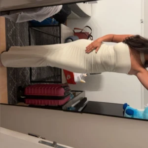 Champagnefärgad axelbandslös långklänning - Säljer en elegant axelbandslös långklänning i champagnefärg. Klänningen har figurnära passform och en slits på baksidan som ger en snygg siluett. Perfekt för dig som vill sticka ut med en stilren och modern look.