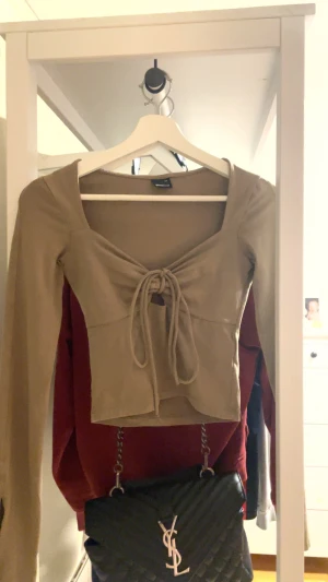 Söt brun långärmad tröja med snörning - Jag säljer min urringade tröja med snörning då jag inte har användning av den längre. Orginal pris var 300. snöret går att justera till hur du vill ha de. Xs men kan passa S. Den har öppna ärmar längst ner