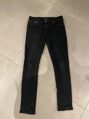 Nudie jeans svarta - Tja säljer nu ett par feta Svarta jeans från Nudie  med slim passform och klassisk femficksdesign. Jeansen har svarta sömmar, knapp och dragkedja framtill  Perfekt för dig som gillar en clean och stilren look. Skicket är helt perfekt som nytt ungefär och storleken är w30 l30 passar dig som är runt 170-180cm lång skulle jag tro!! Har du några övriga frågor är de bara att höra av sig🙌🏼mvh em_resell🤩