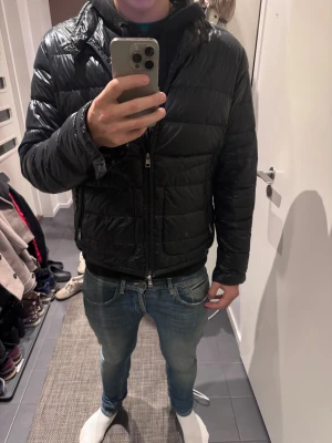 Svart Moncler dunjacka herr - Säljer en mörkblå acorus från Moncler med glansig finish och klassisk logga på ärmen (hundra procent äkta verifierad på monclers hemsida. Jackan har quiltad design, dragkedja framtill och två sidofickor. Perfekt för kalla dagar och har en snygg, normal passform som funkar till jeans och hoodie. 