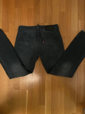Levi's 501 mörkgrå jeans straight fit - Säljer ett par Levi's 501 jeans i mörkgrå tvätt med klassisk straight fit. Jeansen har fem fickor, knappgylf och den ikoniska läderpatchen bak i midjan. Materialet är slitstarkt denim och passformen är normal. Perfekt för dig som gillar tidlös stil. Kontakta vid eventuella frågor!😁