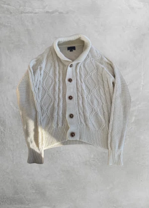 Vit stickad Cardigan❄️⛄️ - Säljer en krämvit stickad cardigan med grovt kabelstickat mönster, stora ribbade muddar och snygg sjalkrage. Koftan har träfärgade knappar framtill och en patch nertill. Perfekt för lager-på-lager under kyliga dagar. Storlek L men sitter som S/M