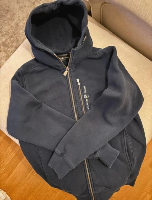 Marinblå hoodie från Sail Racing - Säljer en marinblå hoodie från Sail Racing med dragkedja och huva.