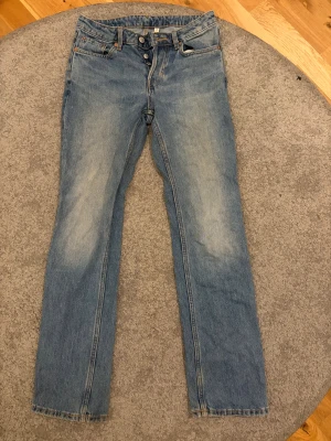 Weekday Pin Mid Straight Jeans 26/32 - Snygga ljusblå jeans från Weekday i modellen Pin Mid Straight. Jeansen har raka ben och midwaist. De har slitna detaljer vid bensluten och är tillverkade i bomull. Perfekt för dig som gillar en chill och tidlös look.