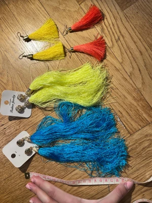 Färgglada tofsörhängen i olika färger - Fyra par statementörhängen med långa tofsar i blått, gult och rött. Två par har guldfärgade detaljer och knäppe, medan de andra har guldfärgade pluppar. Perfekt för dig som vill sticka ut med färg och cool design.