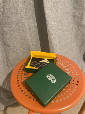 Svart korthållare med mönster - Snygg svart korthållare med det klassiska rutiga mönstret i vitt. Kommer i grön ask och med gul putsduk. Perfekt för kort, stilren och lyxig design. Slimmad form som passar i fickan.