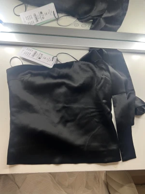 Svart satin tubtopp med knytband - Snygg svart tubtopp från Gina! Ny skick som man ser med lapp kvar!