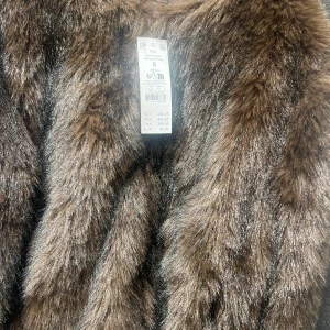 Brun pälsjacka i syntet S - Säljer en fluffig brun pälsjacka från Gina tricot i storlek S. Jackan har en snygg oversized look och är gjord i mjukt syntetmaterial som ger en lyxig känsla. Perfekt för dig som vill sticka ut och hålla dig varm under kalla dagar. Använd fåtal gånger och ser helt ny ut.