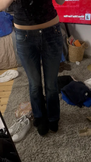 Weekday Flare Low Flared Jeans W27 L32 - Säljer ett par mörkblå Weekday Flare Low Flared Jeans med snygga slitningar och kontrastsömmar. Modellen har låg midja och bootcut-ben som ger en cool siluett. Klassisk femficksdesign och tillverkade i jeansmaterial.