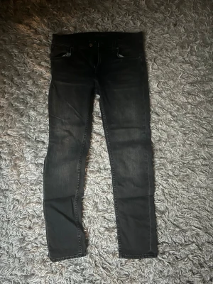 Nudie Jeans Lean Dean Black Eyes - Mörk gråa jeans från Nudie Jeans som är i slim fit. Storleken är 30/30 och dem är i ett bra skick.