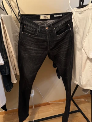 Svarta Replay jeans  - Snygga svarta jeans från Replay, modell Willbi med regular slim fit. Jeansen har klassisk femficksdesign, svarta sömmar och diskret Replay-logga vid fickan. Passformen är slim och materialet är slitstarkt jeans. Perfekt för dig som gillar stilrena och smala jeans.
