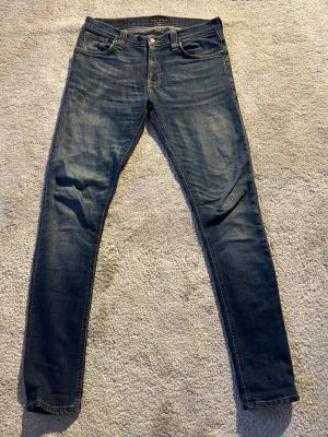 Mörkblå jeans från Nudie - Snygga mörkblå jeans från Nudie Jeans i modellen Tube Tom. De har en snygg och  skön wash. Litet hål i en av fickorna som knappt märks men annars inga defekter alls😁