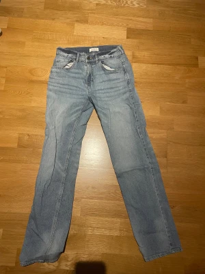 Ljusblå jeansbyxor från Lindex 158 barnstorlek - Snygga ljusblå jeansbyxor från Lindex med klassisk femficksdesign och raka ben. Jeansen har normal passform och är tillverkade i mjukt denimtyg som ger en avslappnad vibe. Perfekta för dig som gillar enkel och tidlös stil.