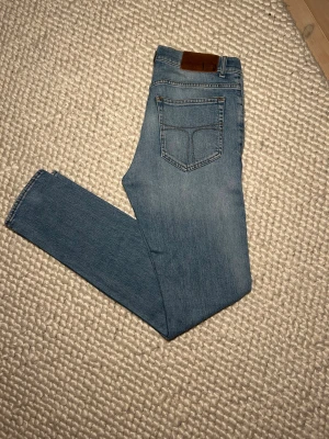 Ljusblå slim fit jeans Evolve 30/34 - Snygga ljusblå jeans från Evolve i modellen Outcast, storlek 30/34. De har klassisk femficksdesign, smal passform och är tillverkade i mjukt jeanstyg. Perfekt för dig som gillar en modern och slim look.