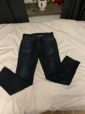 Levi's 511 mörkblå jeans straight fit - Säljer ett par klassiska Levi's 501 jeans i mörkblå tvätt med raka ben och fem fickor. Jeansen har normal passform och är tillverkade i slitstarkt bomullsjeansmaterial. Perfekt för dig som gillar tidlös stil och vill ha ett par jeans som funkar till allt. Är ungefär W29 L32
