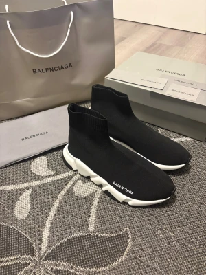Balenciaga Speed Trainer sneakers svart - Säljer ett par Balenciaga Speed Trainer sneakers i svart med vit chunky sula. Strumpliknande design i stickad syntet, med Balenciaga-logga på sidan och hälen. Supersnygga och bekväma, perfekta för dig som gillar streetwear och lyxiga detaljer.