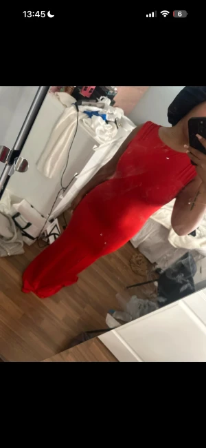 Röd långklänning med tight passform - Säljer en snygg röd långklänning som sitter tight och framhäver figuren. Klänningen är ärmlös med rund halsringning och har en enkel, stilren design utan mönster eller detaljer. Perfekt för dig som vill sticka ut med en klassisk look.
