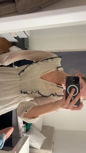 Vit prickig volangklänning från Zara - Supersöt vit kortklänning från Zara med svarta prickar, volanger och svarta kanter. Klänningen har långärmade ärmar, v-ringning och omlottkänsla framtill. Andvänd 1 gång!!