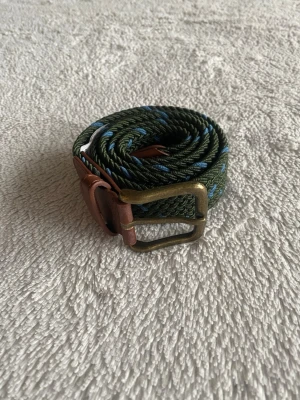 grönt och blått flätat bälte. - Snyggt grönt och blått bälte från. Fick den i julklapp men nu är den för kort.