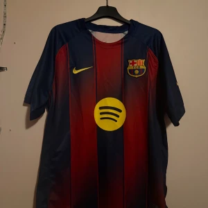FC Barcelona Rashford 14 matchtröja - Säljer en officiell FC Barcelona fotbollströja från Nike med Rashford och nummer 14 på ryggen. Tröjan har klassiska blå och röda ränder, gula detaljer och klubbmärke på bröstet. 