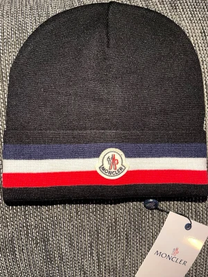 Moncler beanie - Snygg svart Moncler mössa med. Stickad i mjukt material som håller dig varm och stilsäker. Perfekt accessoar för kyliga dagar. Använd några gånger annars som ny