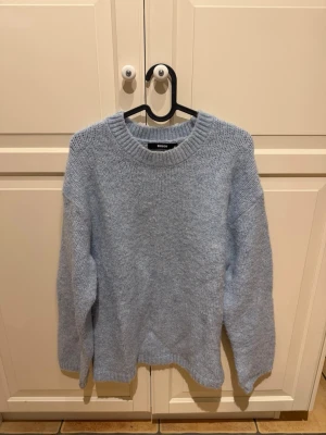 Ljusblå stickad tröja från Bik Bok - Mysig ljusblå stickad tröja från Bik Bok med rund hals och långa ärmar. Tröjan är oanvänd. 