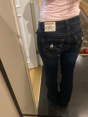 True Religion Becca Bootcut Jeans - Mörkblå jeans från True Religion, modell Becca Mid Rise Bootcut i storlek 25 säljer de då de är för stora o ej den modellen jag vill ha.Färgen har försvunnit längst ner dock på byxorna som ni ser på bilden. Köp!! pris kan diskuteras !  🩷