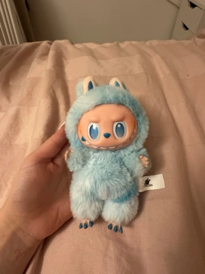 Äkta Labubu från Pop Mart  - Säljer en söt ljusblå pälsväst till Pop Mart-docka från The Monsters-serien. Västen är superfluffig med små öron och detaljer i vitt och blått, perfekt för att ge din samlarfigur en gullig och unik look. Materialet är mjuk syntetpäls. ‼️ Äkta‼️