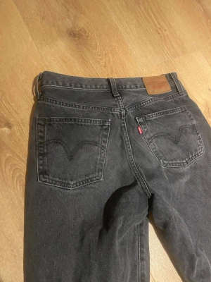 Levi's Premium svarta straight jeans - Svarta Levi's Premium jeans med klassisk femficksdesign och raka ben. Jeansen har en snygg mörk tvätt, tydlig Levi's-lapp bak i midjan och röd Levi's-tag på bakfickan. Materialet är slitstarkt denim och modellen har normal passform. 27/32 och med topp kvalite