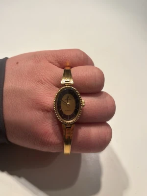 Tunn klocka i guld  - Enkel klocka, i guld lite retro. 