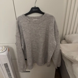 Grå stickad tröja från Gina Tricot - Mysig grå stickad tröja från Gina Tricot med rund halsringning och ribbade muddar. Perfekt för lager-på-lager och chill dagar. Enkel och stilren design som funkar till det mesta.