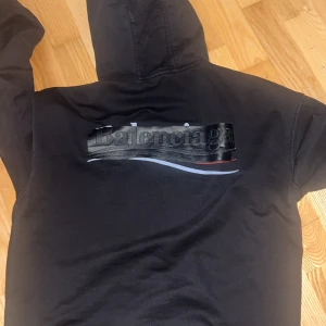 Svart Balenciaga hoodie med tryck - Svart hoodie från Balenciaga med stort tryck på ryggen och mindre logga framtill. Äkta köp för 11k o säljer då jag inte vill ha kvar den längre helt enkelt