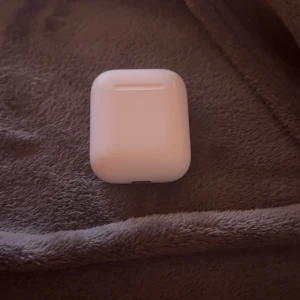 AirPods 2 - Säljer ett par Apple AirPods 2 med laddningsetui. Hörlurarna är i gott skick och fungerar som de ska. Laddningsindikatorn lyser grönt. Mindre tecken på normalt bruk kan förekomma, men inga synliga större repor eller skador.