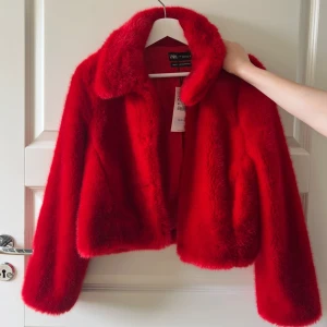 Röd pälsjacka från Zara XS - Säljer en riktigt snygg röd pälsjacka från Zara i storlek XS. Jackan är fluffig och har en klassisk krage, helröd färg och är tillverkad i mjuk syntetpäls. Perfekt för dig som vill sticka ut och hålla dig varm med stil. Helt ny och oanvänd 