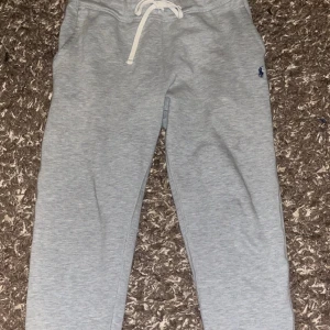 Grå mjukisbyxor från Polo Ralph Lauren - Snygga grå mjukisbyxor från Polo Ralph Lauren med en liten broderad logga på sidan. Byxorna har en bekväm passform med snörning i midjan för justerbarhet. Perfekta för en avslappnad stil. Storlek M, äkta och  kostar 2 tusen nypris