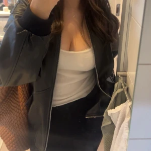 Svart bomberjacka från Noisy May - Svart bomberjacka från Noisy May i skinnimitation med ribbade muddar och silverfärgad dragkedja. Jackan har två fickor. Avslappnad passform på mig som är 168cm. Använd 1 gång därav nytt skick. Nypris ca 500kr.