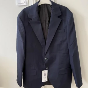Mörkblå kavaj från Jack & Jones -  Säljer en HELT NY  mörkblå kavaj från Jack & Jones i modellen JPRFRANCO Blazer. Oanvänd med ettiket och förpackning. Nypris 1210kr  