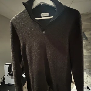 Brun merinoullströja från These Glory Days - Säljer en brun långärmad tröja från These Glory Days i mjuk merinoull. Tröjan har en hög krage med half zip-dragkedja och stilren design. Perfekt för lager-på-lager under kyliga dagar.