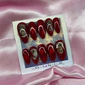 SantaCats (M);Medium Almond - Snygga lösnaglar i en medium mandelform med djup röd bas, glitterstjärnor och detaljerade kattmotiv med tomteluva. Naglarna har en glansig finish och jul-detaljer. Perfekt för dig som vill sticka ut med ett unikt och festligt nagelset.M: 16 mm, 12 mm, 12,5 mm, 11,5 mm, 10 mm