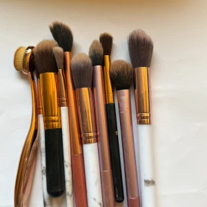 Set med sminkborstar i olika former - Säljer ett set med 10 sminkborstar i olika storlekar och former, perfekta för foundation, contour och ögonskugga. Borstarna har handtag i marmor, svart och roséguld, samt borst i syntetmaterial. Inkluderar både rundade och platta borstar för olika tekniker. 10 för 100 deal