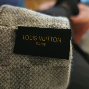 Grå Louis Vuitton mössa i ull - Säljer en exklusiv grå mössa från Louis Vuitton med diskret LV-logga framtill. Mössan är tillverkad i mjuk ull och har en klassisk, ribbad kant. Perfekt accessoar för dig som vill ha en stilren och lyxig look under kyliga dagar.